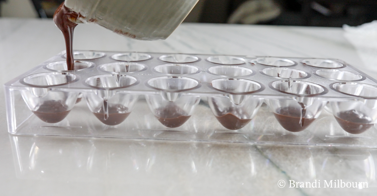 Filling the Mold: First, pour chocolate into each chocolate mold about ¼ full. Next, rotate chocolate mold until sides of molds are completely covered with chocolate. (Wait until all molds are filled before rotating or chocolate will spill out) Use a spoon to cover missed areas. Return chocolate to oven.