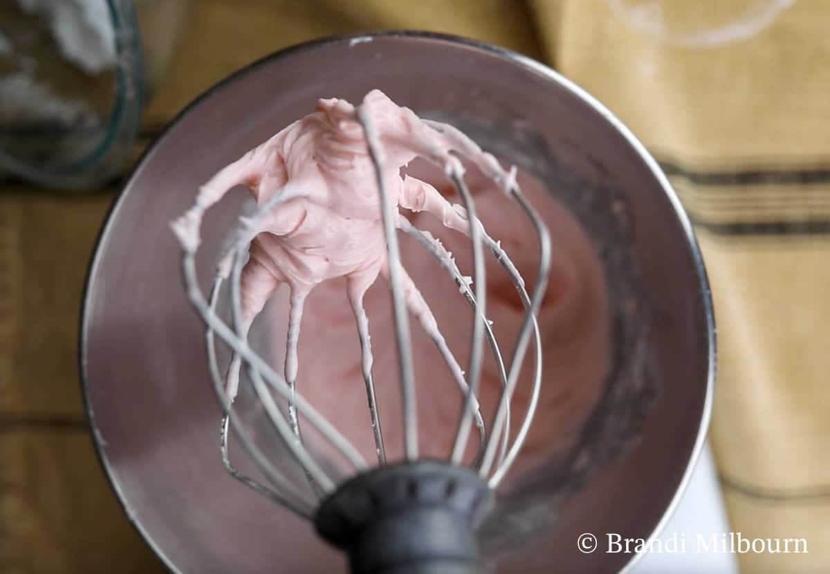 Using a stand mixer, combine sifted powdered sugar, cherry juice, almond extract, and cream of tartar in a mixer bowl. Using the wire whip/whisk, mix together until smooth and scraping down sides as needed.