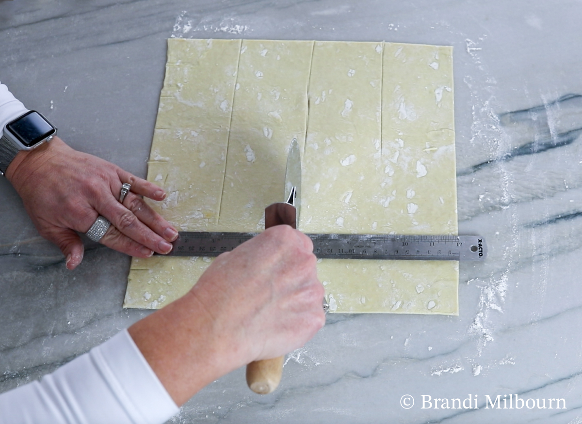 On the top and bottom of the pastry, mark and cut pastry puff every 3 inches wide across the pastry. Then, use the ruler to line up both marks and cut along the ruler’s edge making 3 cuts.