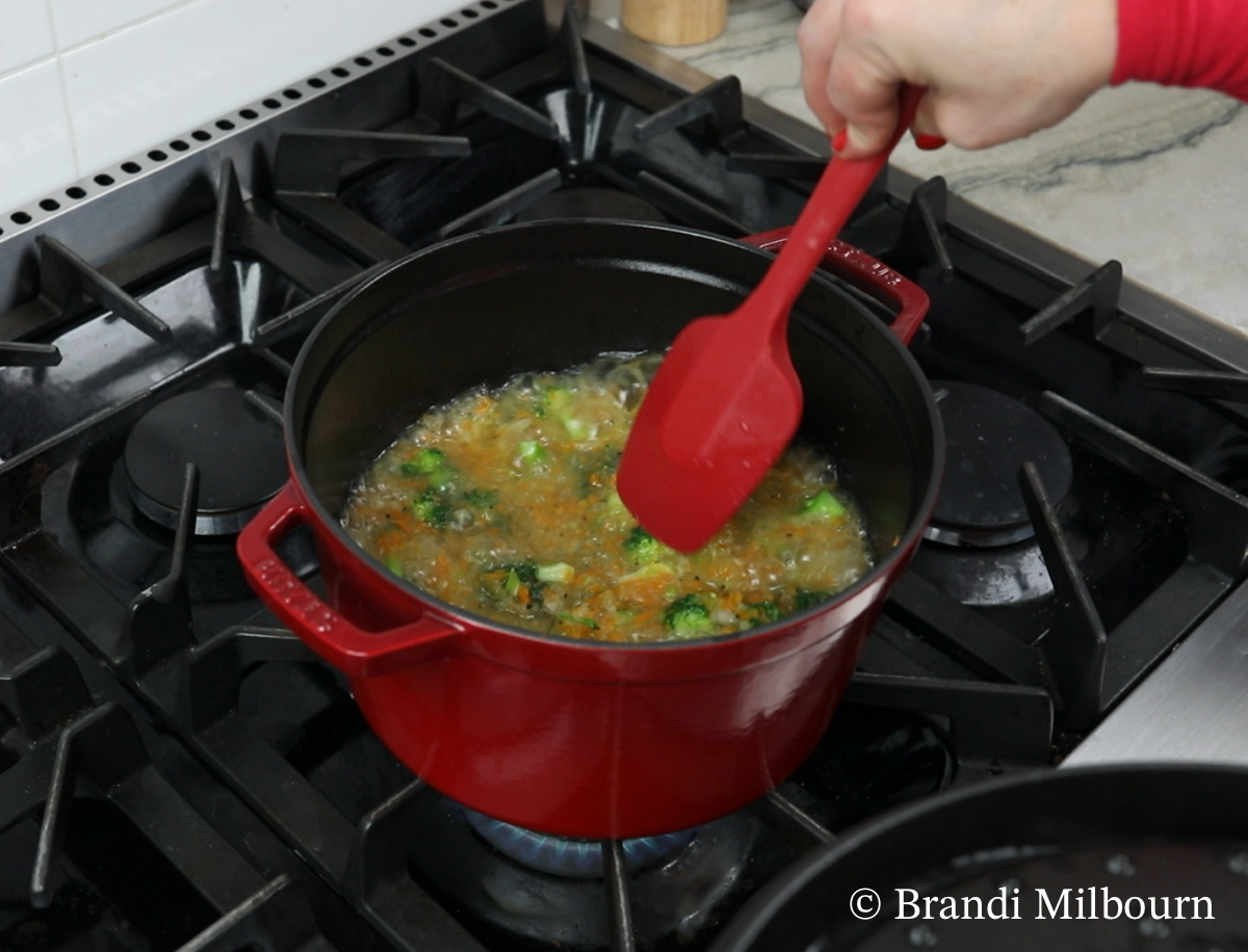 Broccoli cheese soup cooking carrots and broccoli and onions in chicken stock in the stock pot