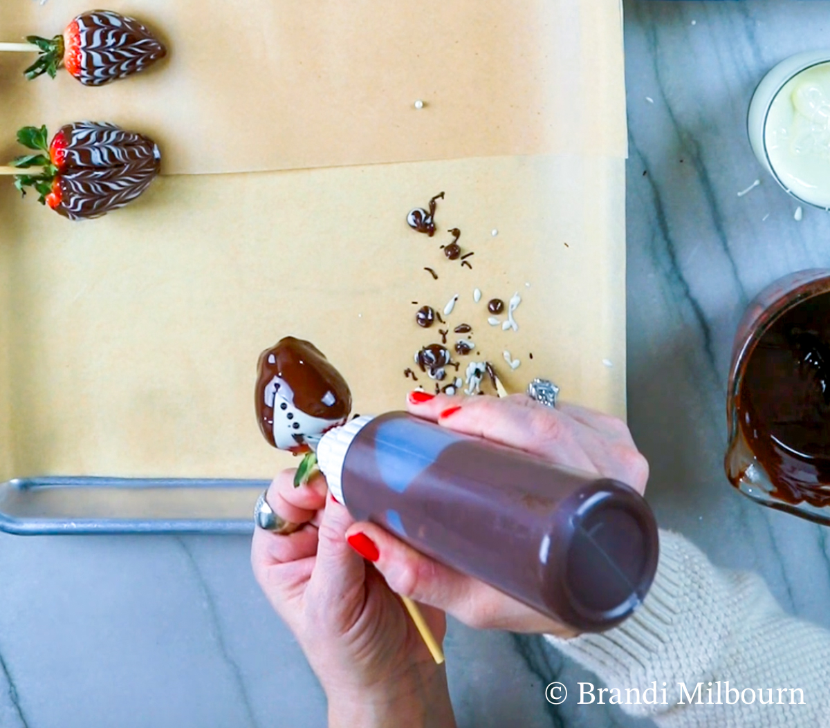 Creating a tuxedo strawberry first covered in white chocolate then with dark chocolate as the suit three buttons and a tie