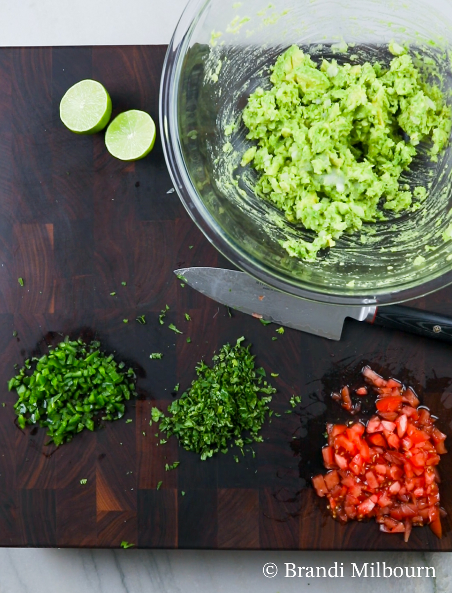 Mashed avocado with chopped vegetables for guacamole