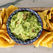 Bowl of guacamole on platter of chips