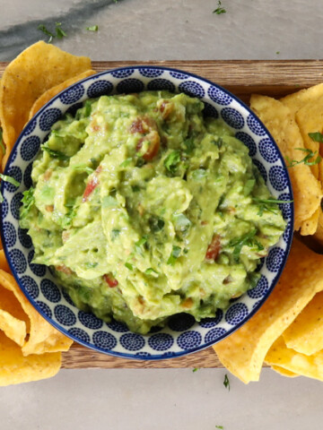Bowl of guacamole on platter of chips