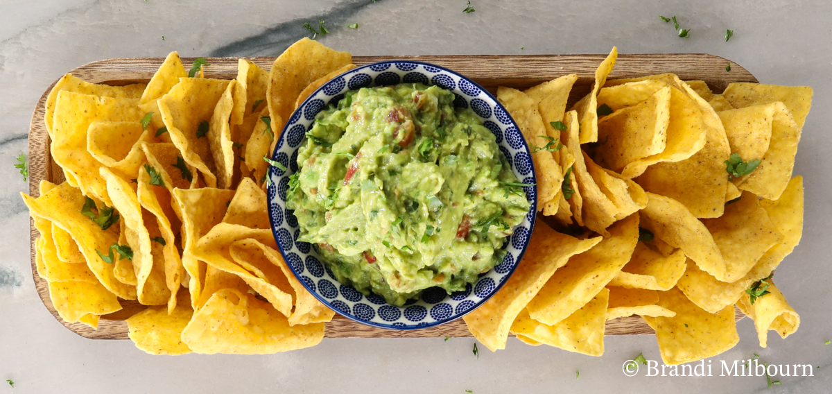 Bowl of guacamole on platter of chips