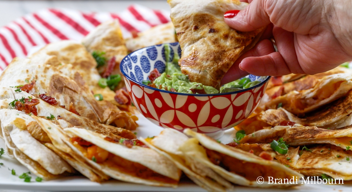 chicken and shrimp quesadillas on a platter with creamy guacamole to dip quesadilla