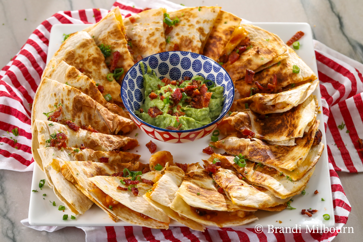 chicken and shrimp quesadillas on a platter with creamy guacamole to dip this delicious quesadilla