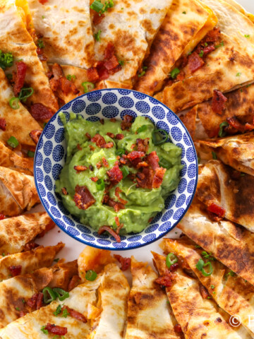 chicken and shrimp quesadillas on a platter with creamy guacamole to dip
