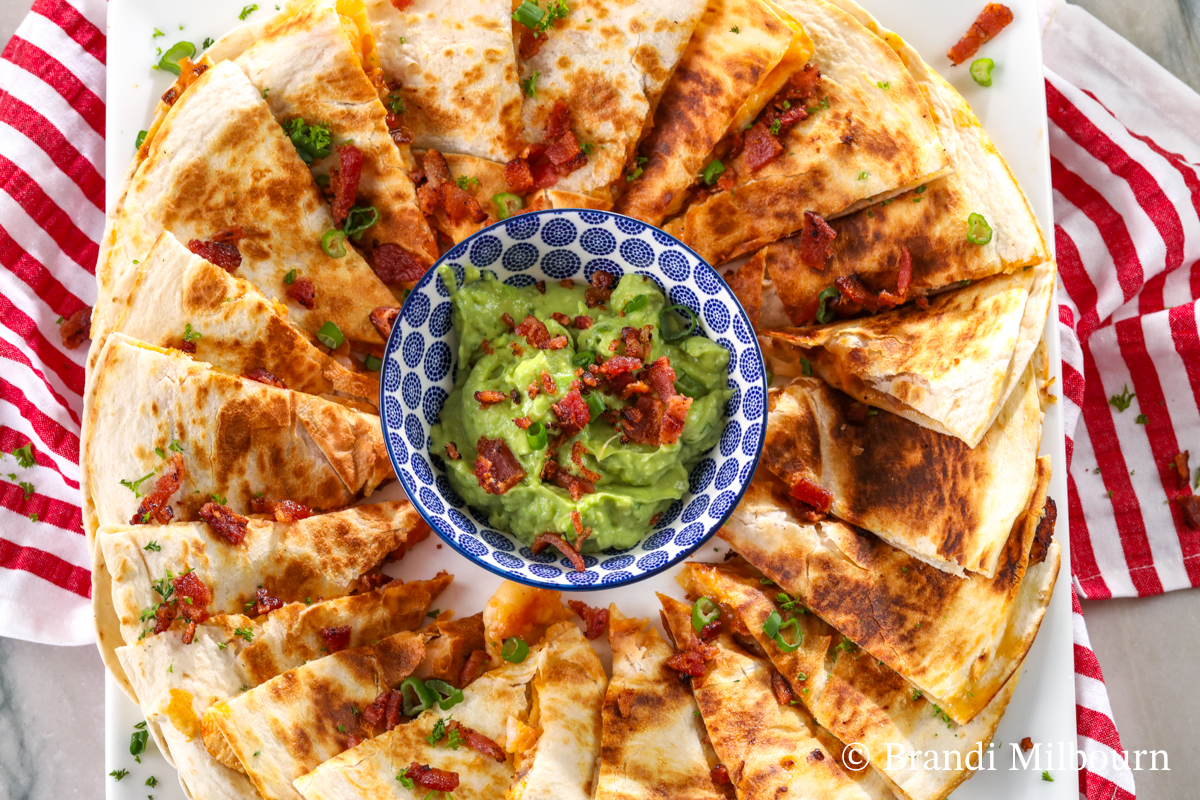 chicken and shrimp quesadillas on a platter with creamy guacamole to dip