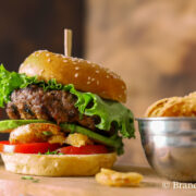 Huge burger with lettuce, deep fried onions, avocado, and tomato