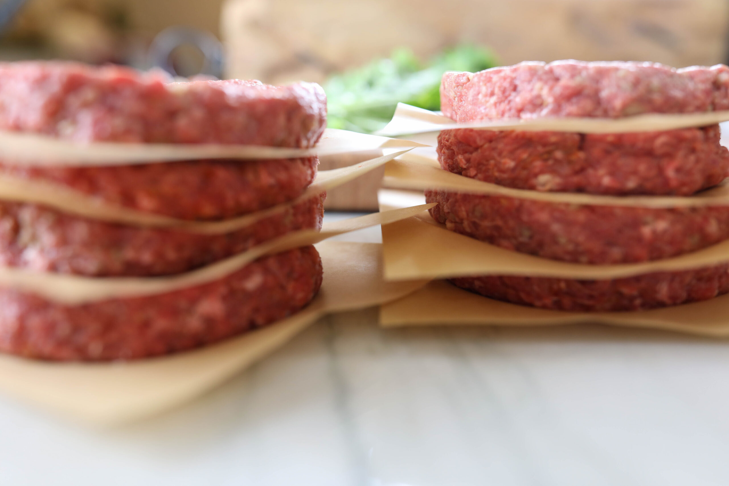 Eight hamburger patties stacked with parchment paper between each layer.